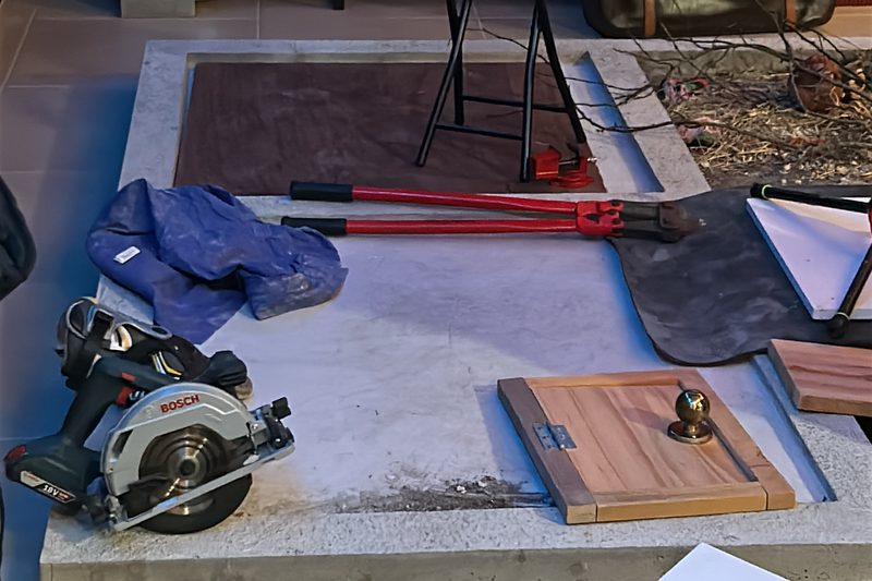 Tools and props laid out beside a Foley pit, including a circular saw, bolt cutters and a small wooden door